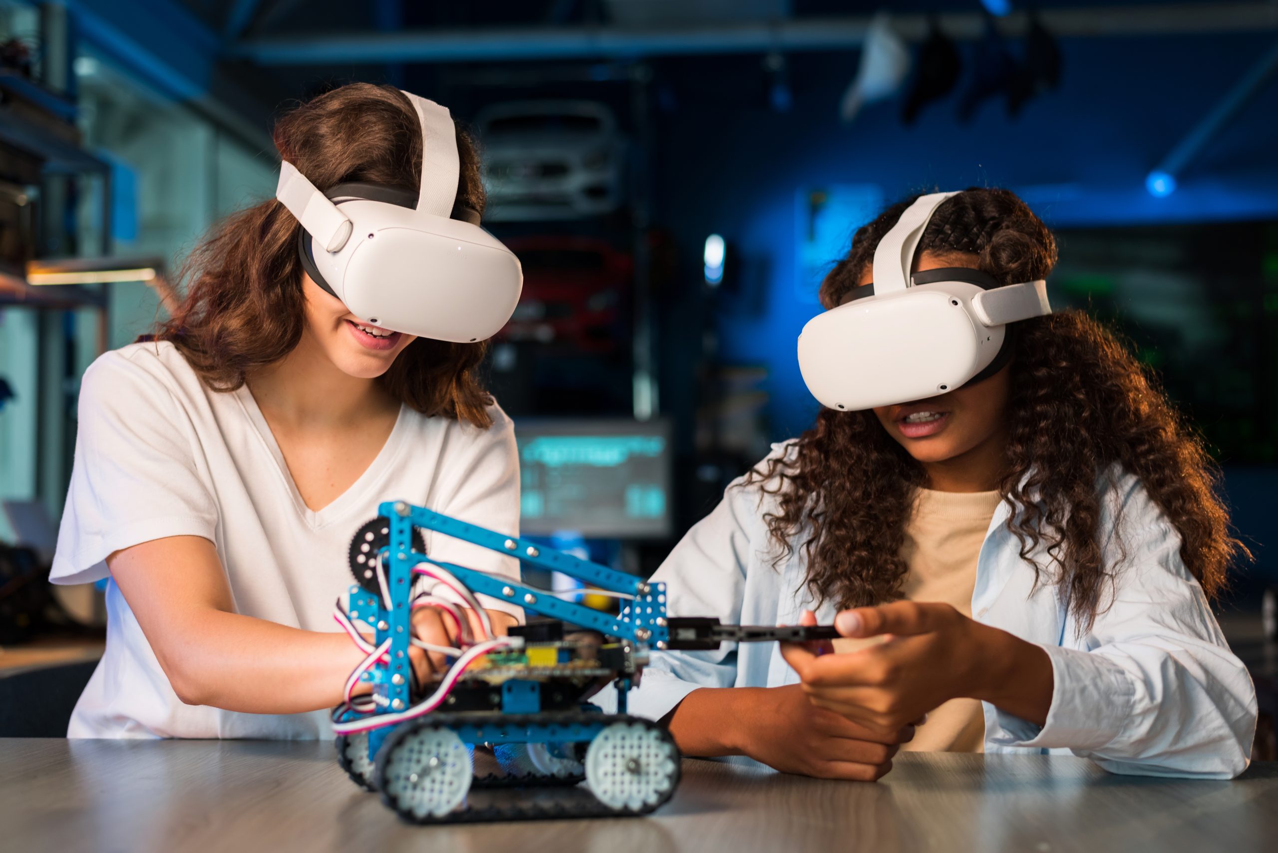 Two young women in VR glasses doing experiments in robotics in a laboratory. Robot on the table
